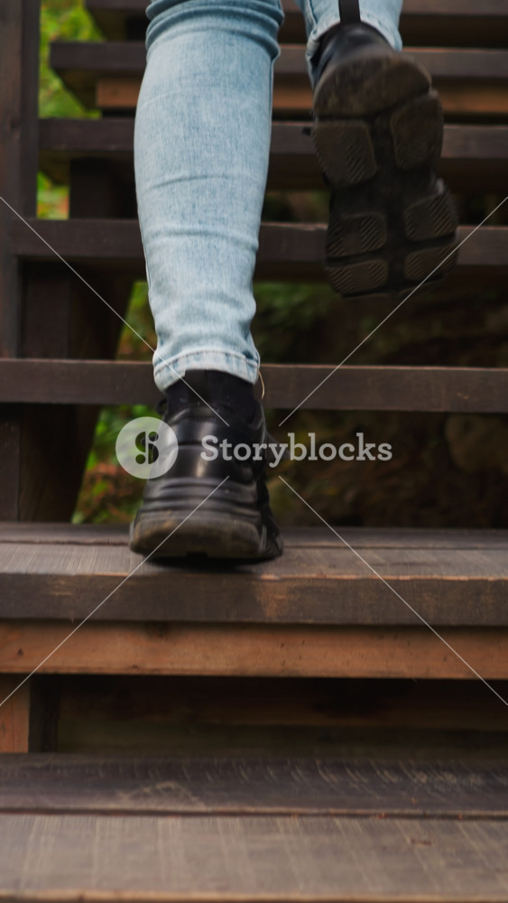 Woman in sneakers stepping from stair to stair. Young lady reaches top of stairs on way to gampling house. Young woman during vacation in