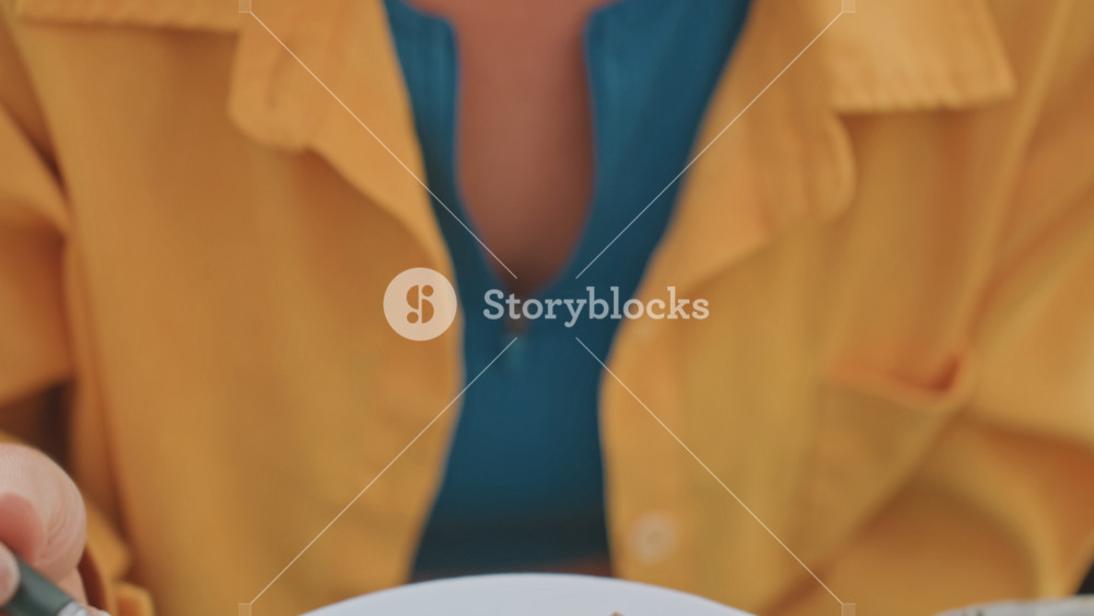 Outdoor camping table mushroom dish, caucasian woman camper tasting sauteed mushrooms, yellow jacket and blue top, freckles visible in