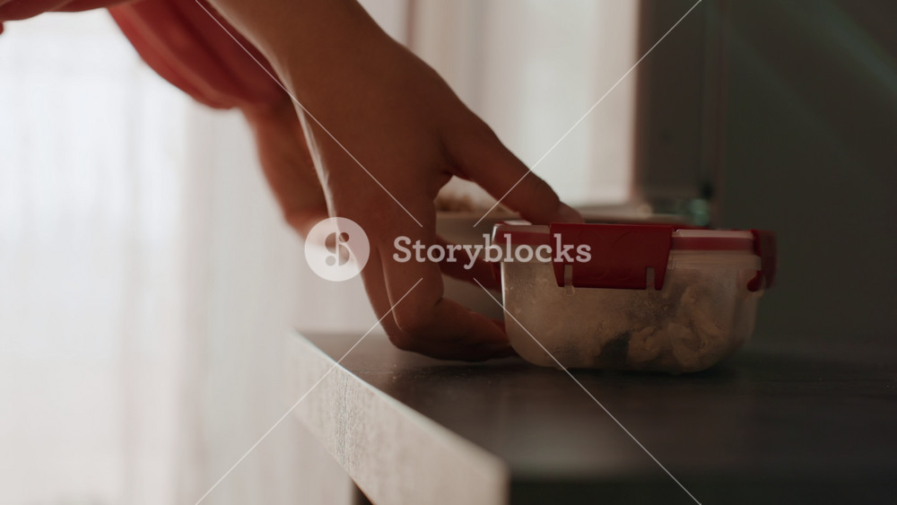 Lady Places Lunchbox, Woman Gently Slides Container, Carefully Moving Lunchbox To Countertop Edge, Woman Carefully Advances Her Lunchbox To