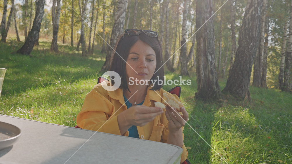 Caucasian woman shares food with her attentive dog outdoors. An outdoor moment between woman and her dog as she shares snacks. Woman offers