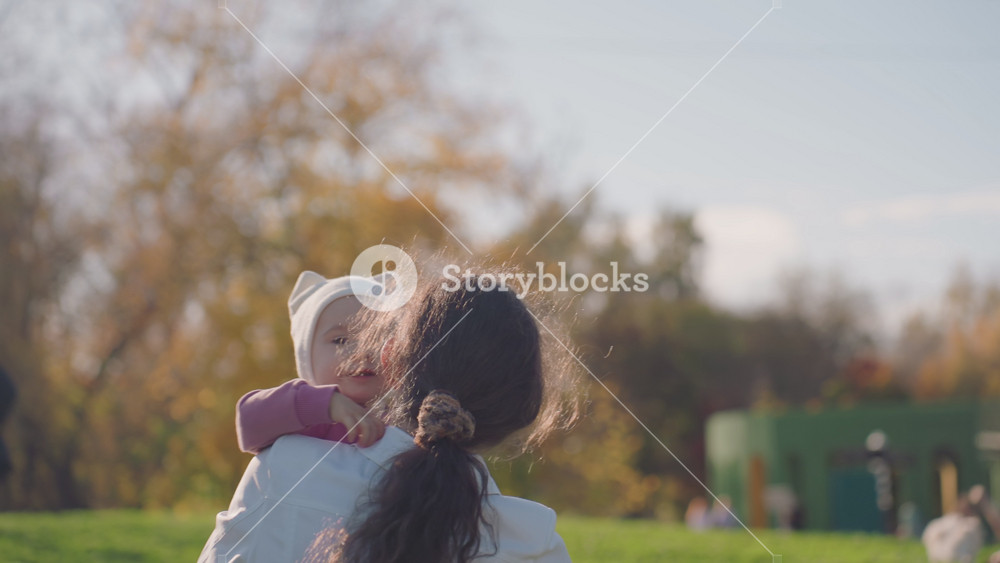 Mother and baby sharing affectionate moment outside. Happy family captured in park with loving expressions and sunlight. Mother tenderly