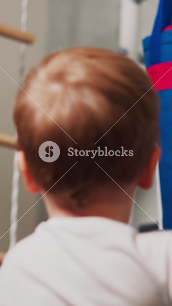 Little boy with boxing gloves punches drawing angry man on heavy bag in playing room closeup. Child deals with stress via sports exercises
