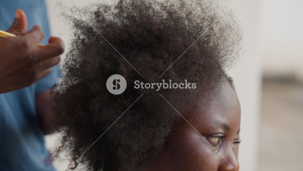 Closeup of woman caring for textured curls. Black woman gently combs coarse natural hair with care. Detailed closeup of stylist tenderly