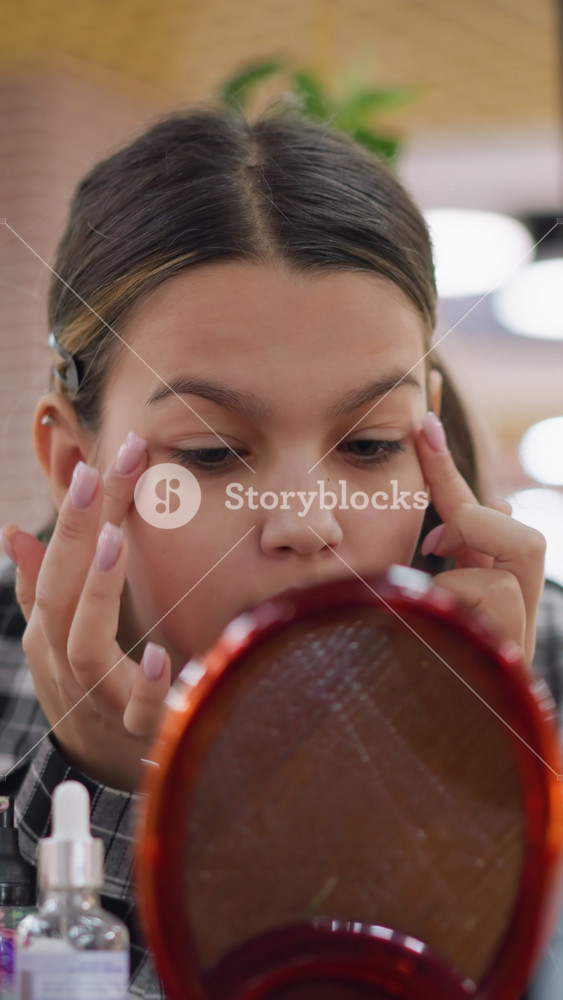 Young girl concentrates on makeup application, Teenager focusing on applying foundation with purple sponge, Young girl meticulously blending