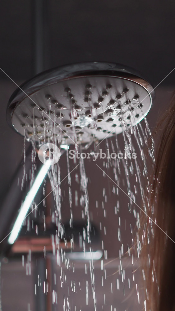 Woman taking hot shower to clean body and head. Lady doing evening cleansing routine in shower. Female brunette enjoys strong pressure of
