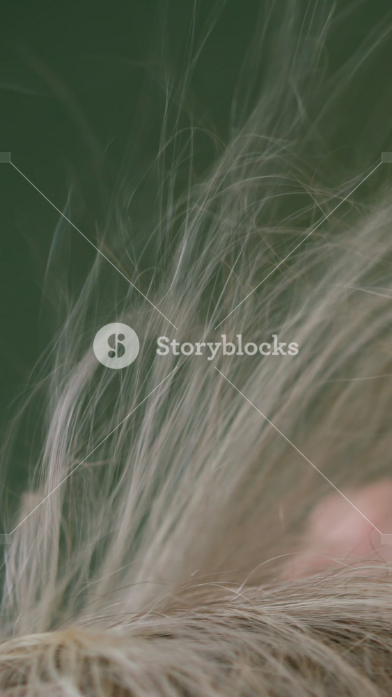 Careful stylist brushes and dries lady client long blonde hair in contemporary professional beauty salon extreme close view slow motion
