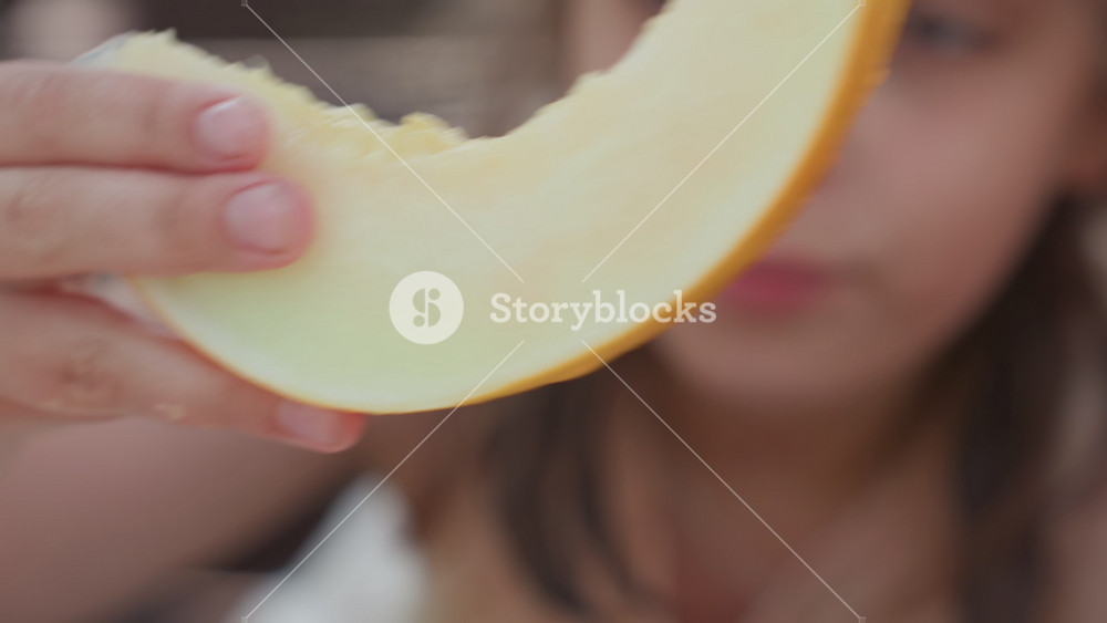Close View Of Girl Savoring Summer Fruits Outdoors, Child Happily Peeling And Tasting Ripe Melon Outside On Porch, Girl Indulging In Juicy