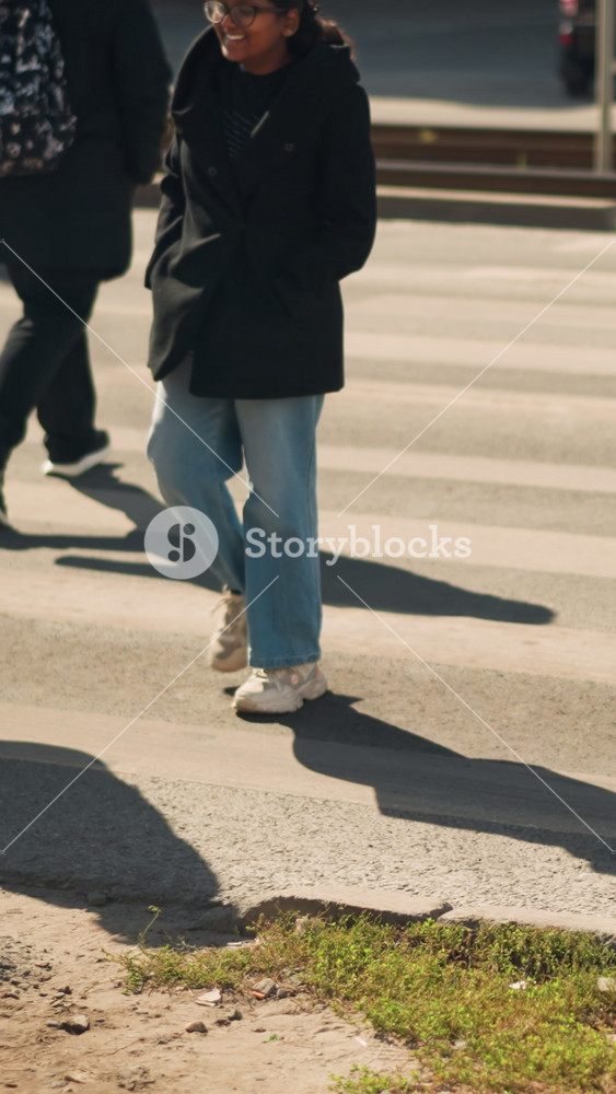 group crossing city crosswalk in sunlight young adults walking in jackets and denim, tote bags and sneakers, rhythmic strides and elongated