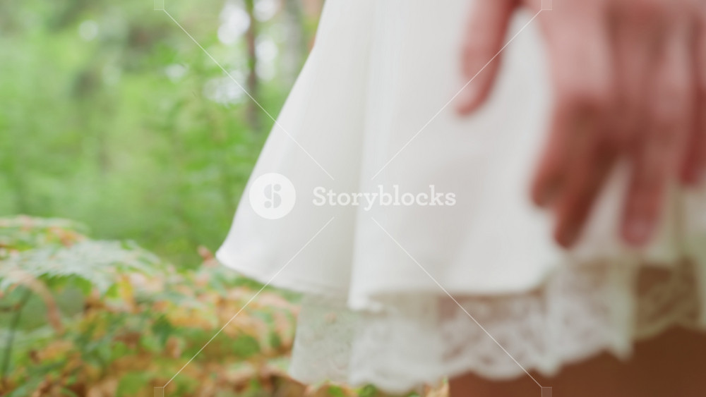 Close up of white fairy lady with large wings walking through green forest, holding wooden staff in hand, surrounded by soft light and lush