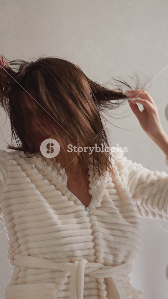 Female visitor of salon throws hair in different directions slow motion. Brunette energetic woman shakes wet hair with hands looking in