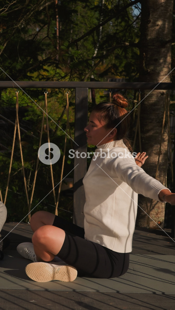 Partners do yoga spreading arms at glamping. Brother and sister breathe deeply fresh air meditating on eco hotel terrace. Body and mind