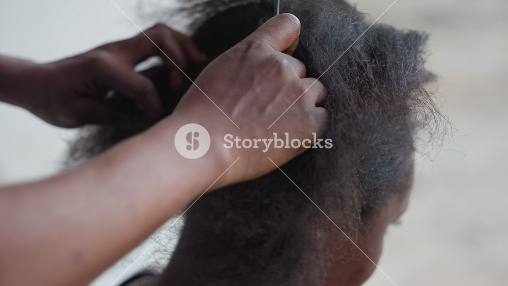 Outdoor hair detangling session. Closeup of family member removing sand from thick hair outdoors. Intimate scene of caregiver carefully