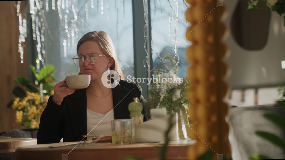 Woman examines coffee. Indoor view of woman inspecting coffee. Bright interior captures woman analyzing steaming beverage. Woman scrutinizes