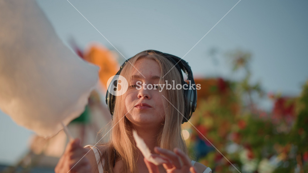 white young woman tasting cotton candy with headphones, intimate fairground closeup, eyes closed in serene ASMR moment, slow savoring of