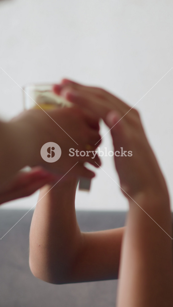 Side view of young girl handing herbal tea to her brother seated on couch, offering care and comfort during illness as he collects and