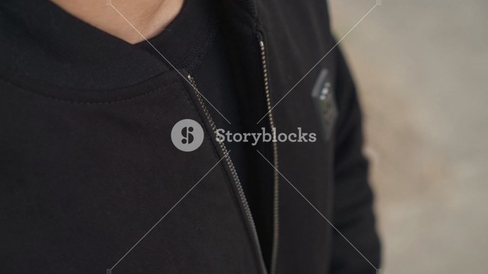 man finetuning zipper on outdoor jacket, detailed shot of male repairing jacket in natural light, close perspective capturing deliberate
