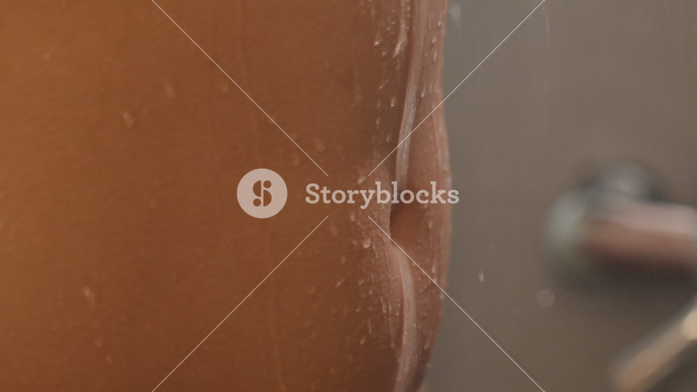 Shower Water Closeup. Water Droplets on Skin in Minimalist Bathroom. Closeup of Shower Water on Skin with Blurred Faucet. Detailed Shot of