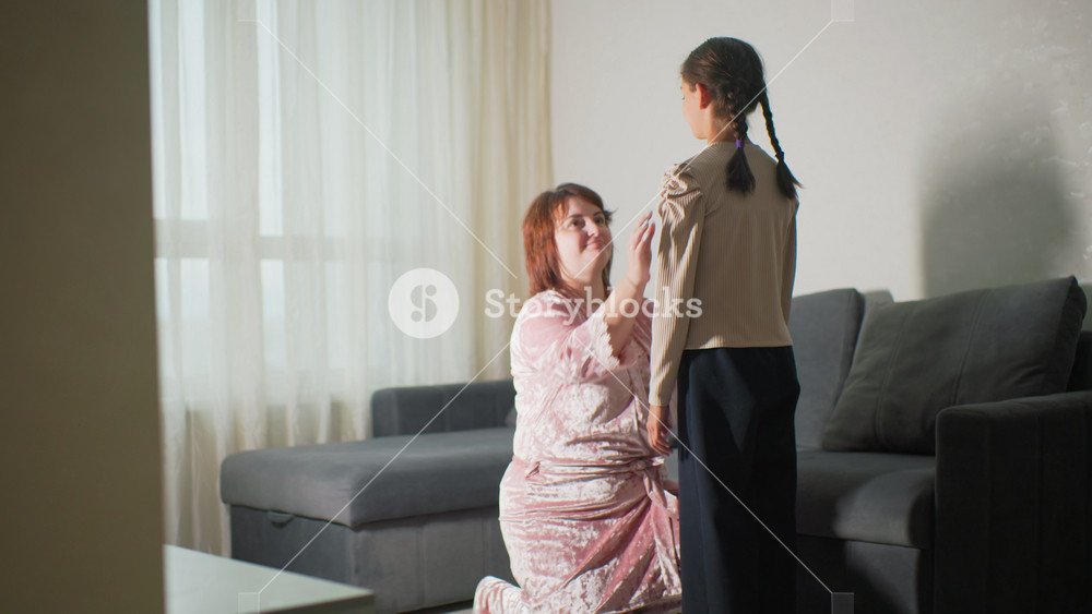 mum braiding daughters hair on sofa in sunlit living room close-up of caring hands weaving pigtails intimate mother child bonding moment