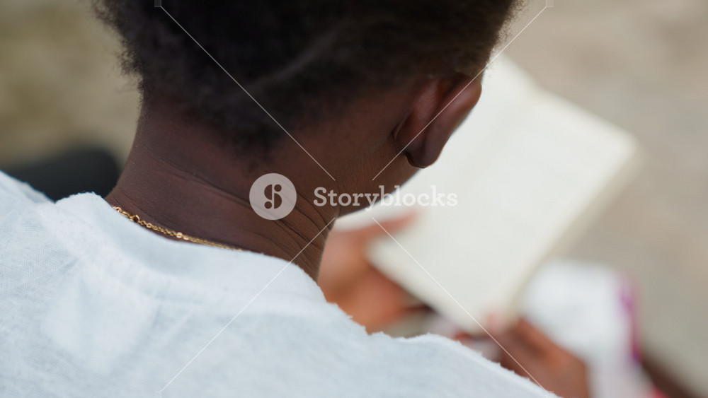 Female reading quietly amidst nature surroundings. Quiet woman with gold chain enjoying her book outdoors. Serene woman in casual attire