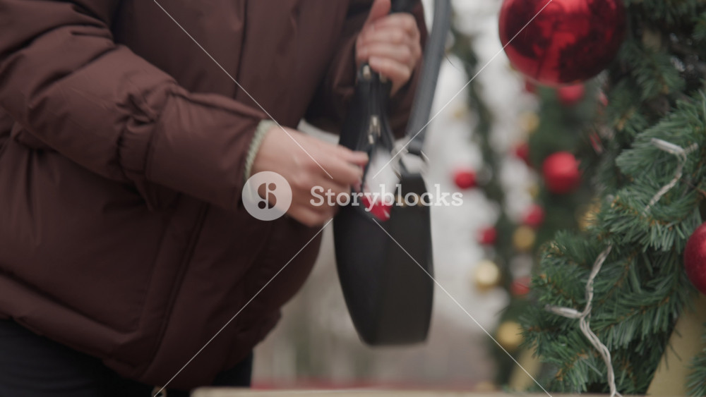 Confident female shopper exits market carrying decorated handbag and plush toy. Stylish woman with red ornaments and plush gnome leaves