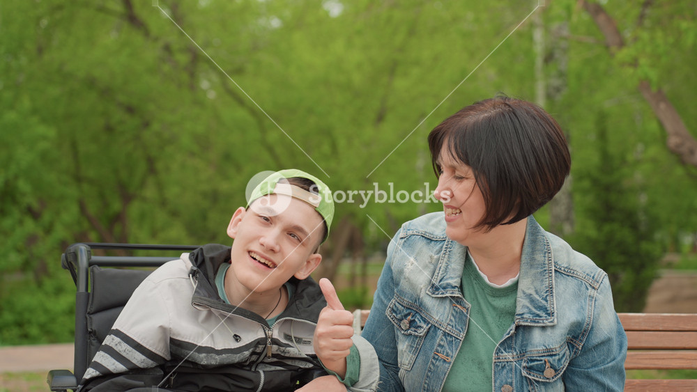 Joyful Supportive Interaction, Woman Shows Support And Cheerfulness To Smiling Teenager In Wheelchair, Vibrant Scene Of Woman Encouraging