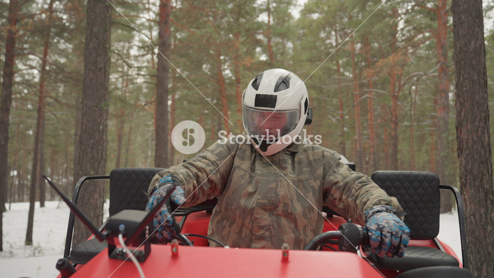 Excited rider prepares for snow journey. Enthusiastic adventurer gears up for winter ATV in snowy woods. Rider equipped for thrilling snowy
