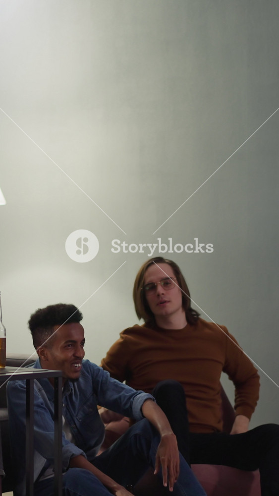 Mad man hipster throws remote in TV and scares emotional friends at football evening slow motion. Dramatic reaction on failure of favorite