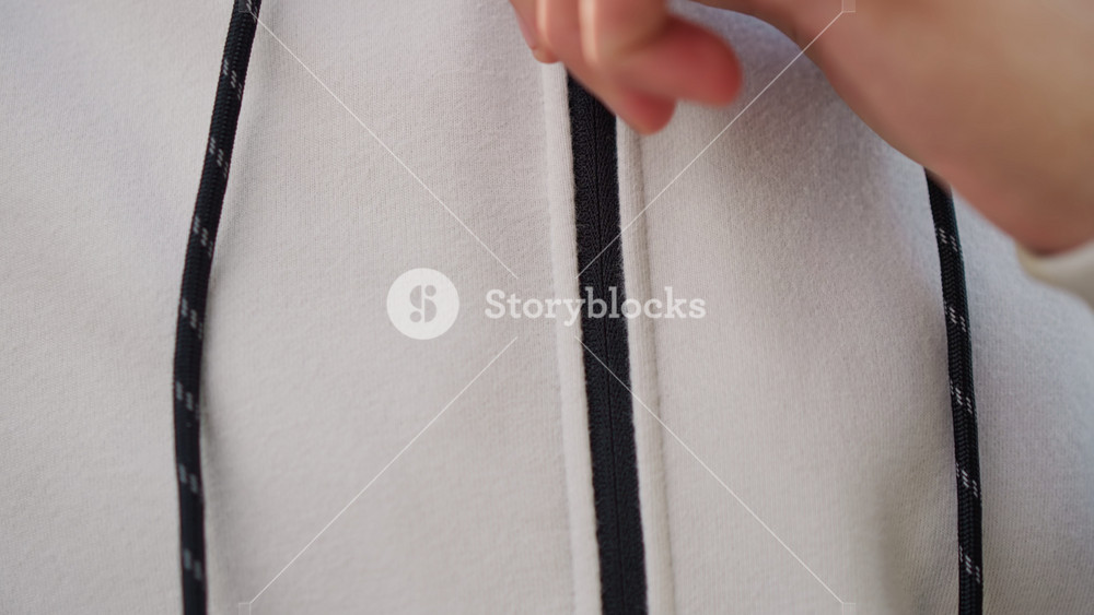 white man fastening hoodie zipper in closeup, tactile focus on hands and textured knit fabric, cord detail and seam seen, runner prepping