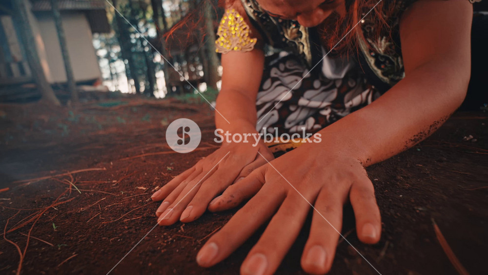 An artistic close-up of a Javanese dancer's hands on the forest floor. The expressive gestures in the soil convey a story of despair, sorrow, and a deep, emotional connection to the earth.