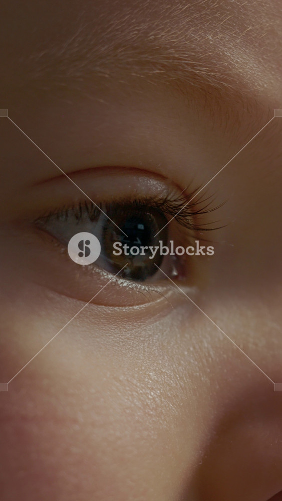 Vertical Screen: A little boy watches TV closely. His eyes are focused on the screen as he takes in the bright colors and sounds from the cartoon playing.