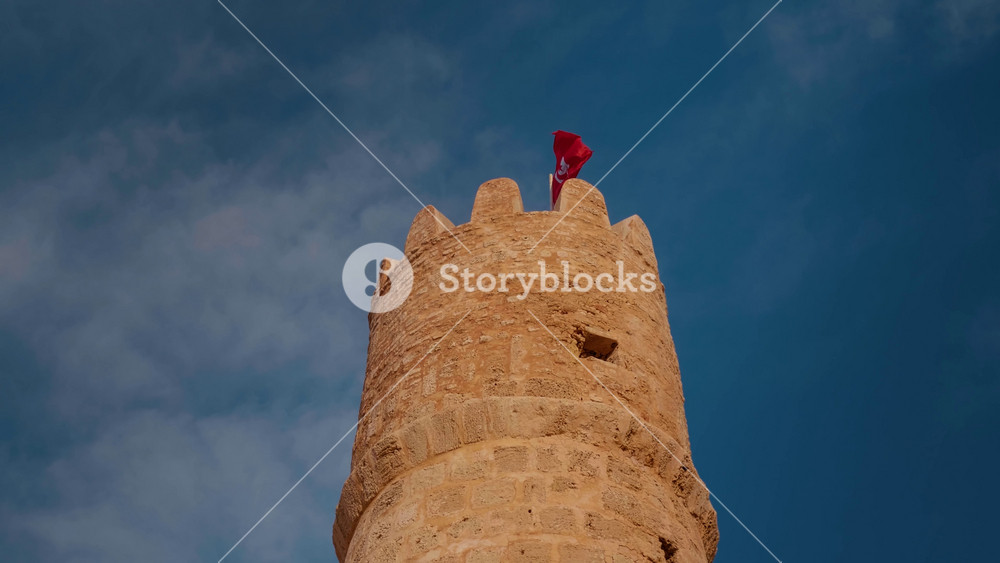 National flag Tunisia waving on wind on top protective fortress Ribat, Monastir. Shot of tower and the sky above in Monastir.