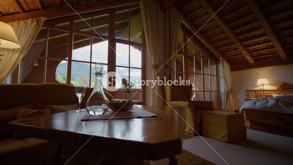 Spacious country house with stylish interior with wooden ceiling and furniture near yellow sofa. Large chalet room with wooden table and cozy decor.