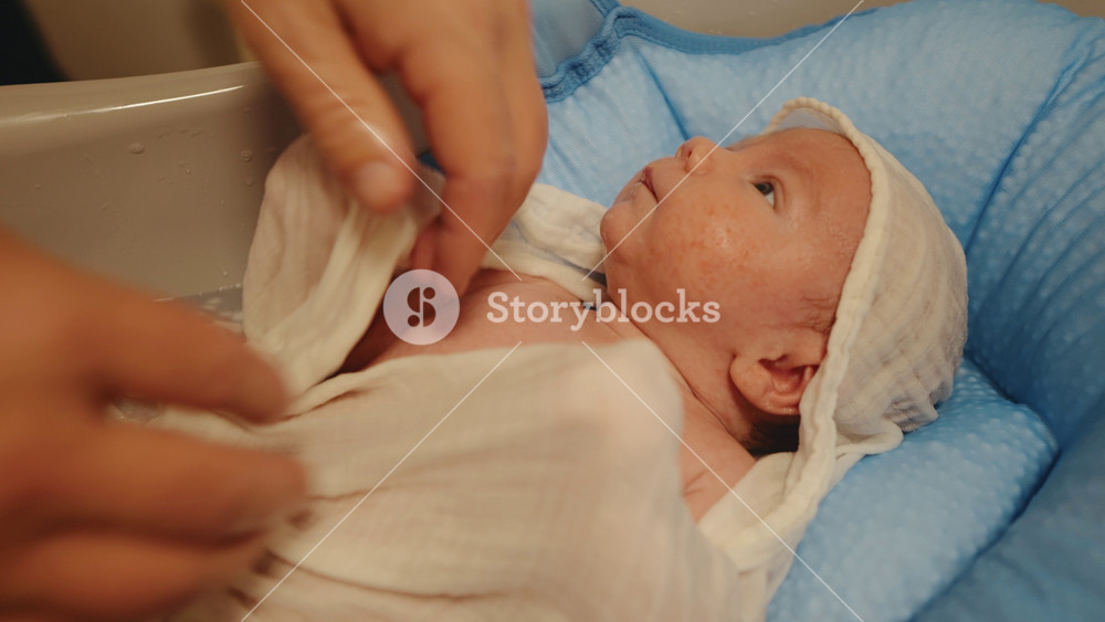 New born nighttime routine of washing the baby carefully. Close- up of infant in a bath before bedtime. Happy family concept.