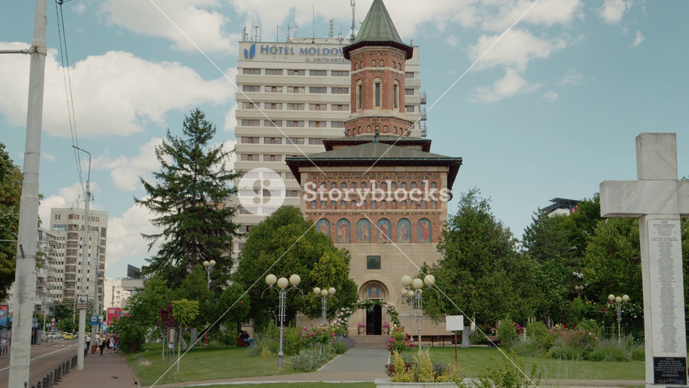 IASI, ROMANIA - June 20, 2026: The Church of Saint Nicholas the Prince in Iasi surrounded by urban buildings and greenery. People walk by as the church stands tall against the city backdrop.