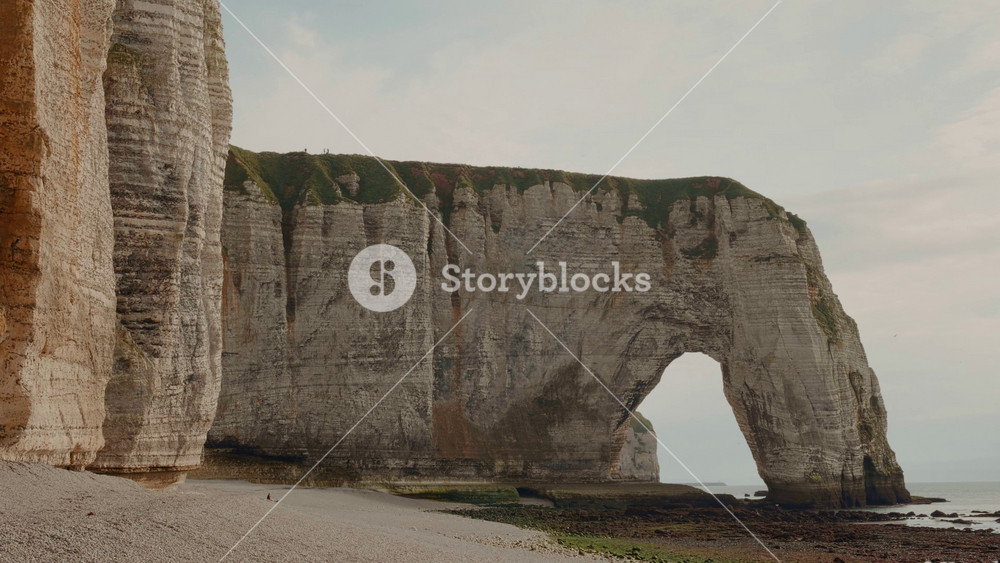 French beach, plage by the towering cliffs and natural arch in Etretat in France. Rock formation by the water edge, scenic point tourist attraction, summer vacation in France.