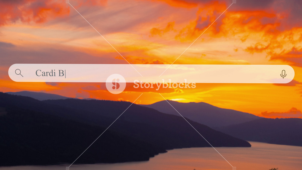 A close-up of a search bar where a person types in 'Cardi B', a well-known singer and actress, on a clear day. The background shows a colorful sunset over mountains.