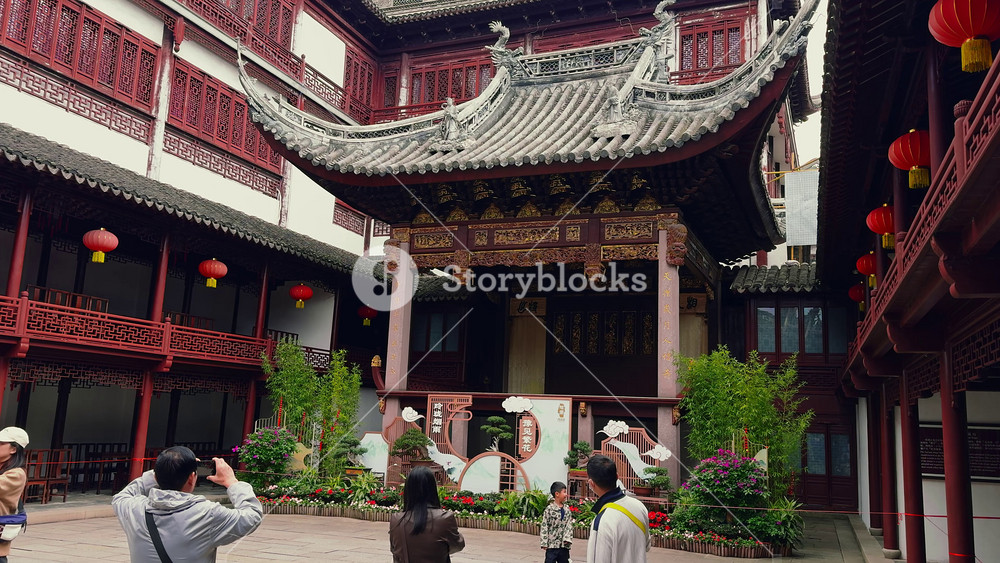 Yu Gardens in Shanghai features intricate wooden carvings, classic roof designs, and red lanterns, with visitors capturing its cultural significance.