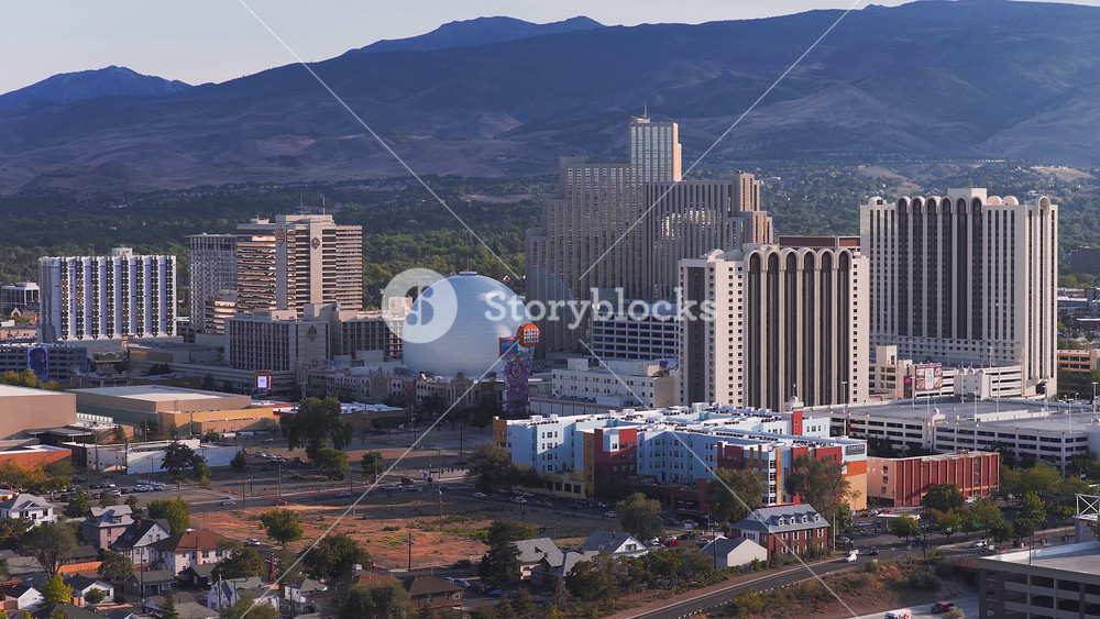 Aerial view of Reno, Nevada, at sunset featuring casinos, high rise buildings, the National Bowling Stadium, and Sierra Nevada mountains in the background.