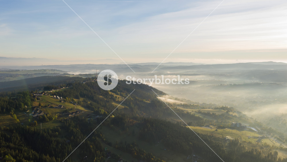 Aerial timelapse hyperlapse flight over amazing hilly landscape lit with warm morning sunlight. Drone shot radio station tower on hill in haze sunrise light. Highlands, clouds of fog moving fast