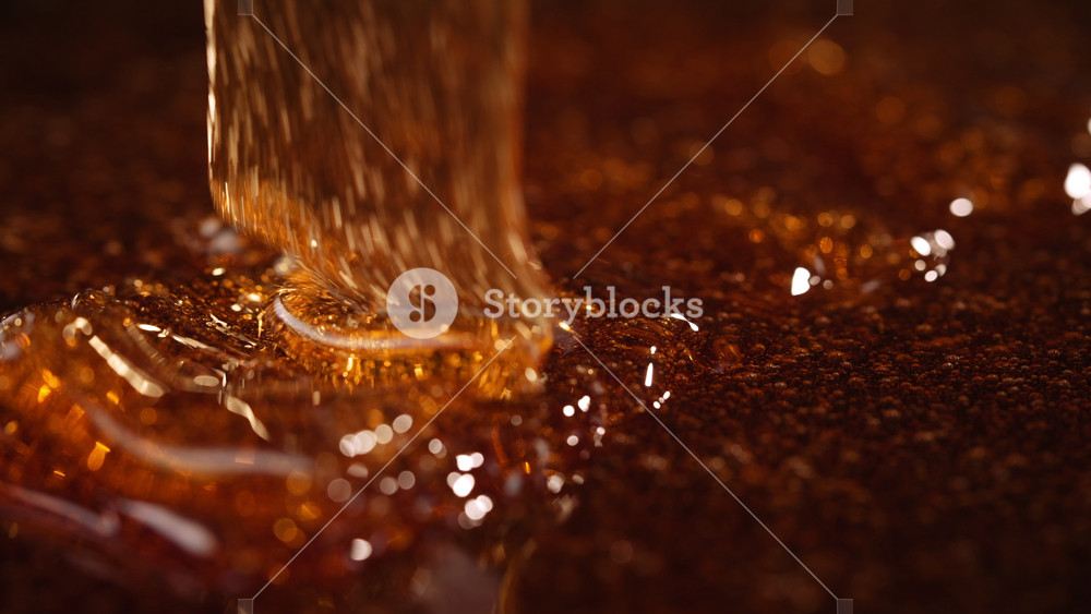 Close-up slow motion shot of pouring yellow caramel or fresh honey, seamless dripping sweet liquid syrup drip flows, thick organic honey dripping, golden caramel sauce flowing waves