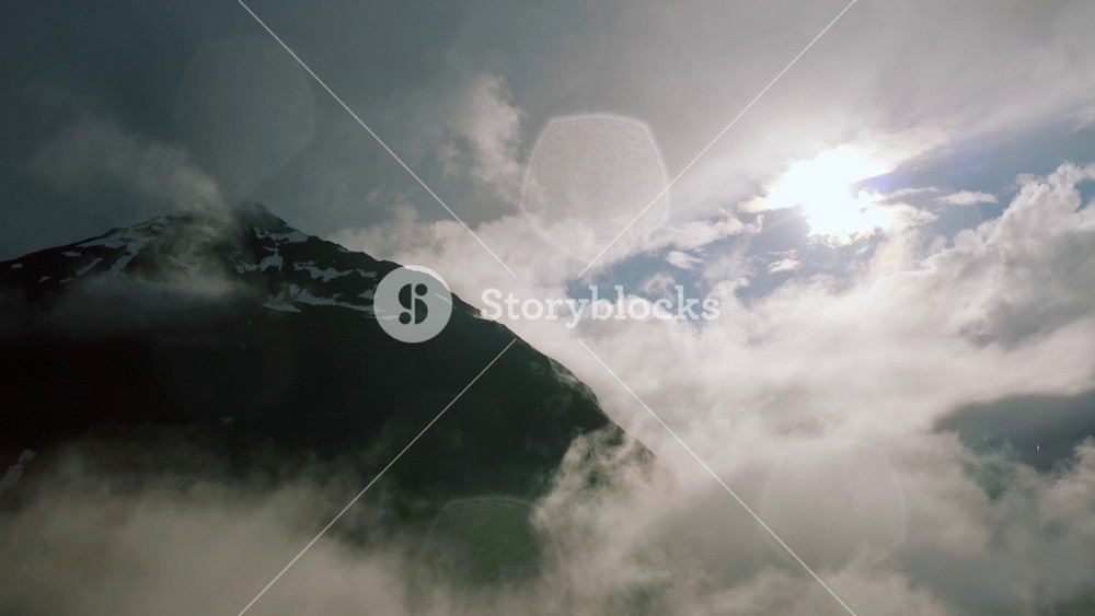 Aerial view of nordic landscape, flyover green valley beautiful formations and mountains covered with rainy clouds in Iceland. Cinematic drone shot of amazing north fjord small lake and winding river