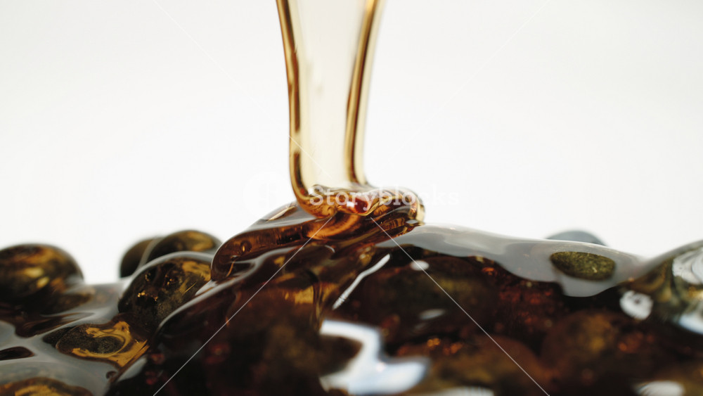 Close-up macro honey pouring on blueberries ripe organic fresh berries on white background dolly slide shot. Caramel flowing, blueberry poured sweet sauce, honey drips over berries