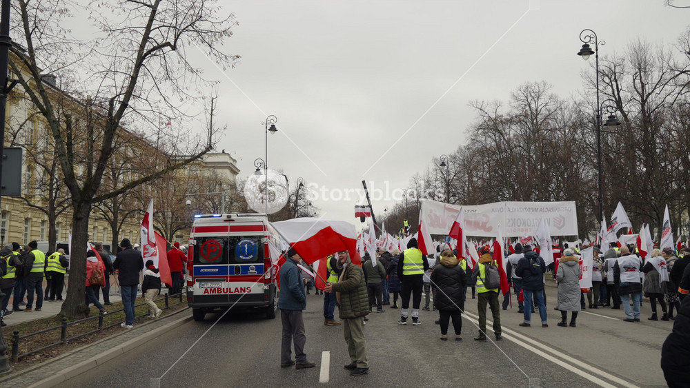 Warsaw, Poland - March 6, 2024: group of people carrying red and white flags on the street, farmers protest, demonstration of protesting agricultural workers, people crowd marching