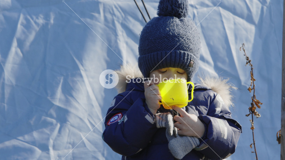 Lviv, Ukraine - March 15, 2022: Refugees at the railway station of Lviv waiting for the train. Little child standing and eating after