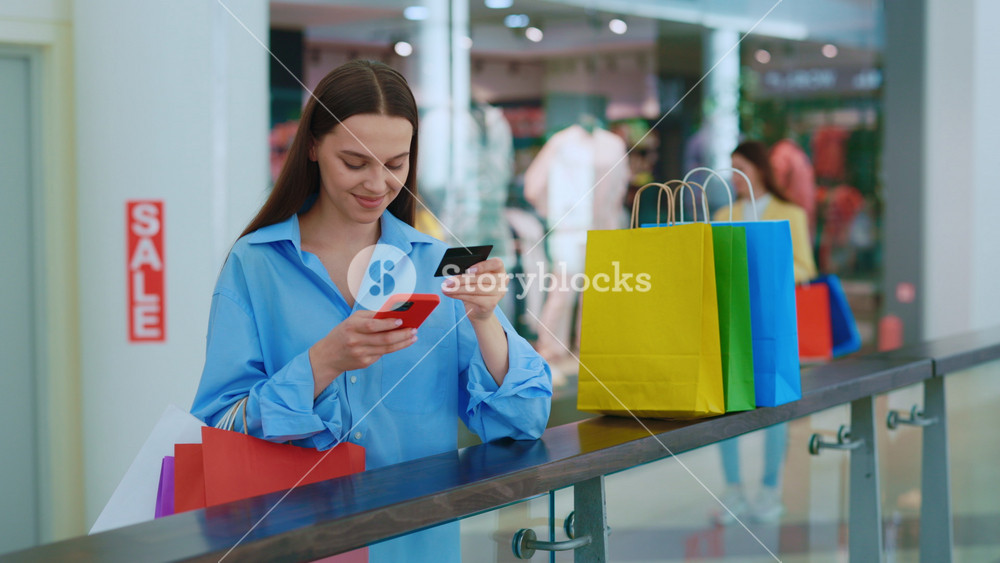 Woman is shopping online on the mall. Credit card in hand of girl. Woman is paying bills. Purchase online by credit card. Female makes an