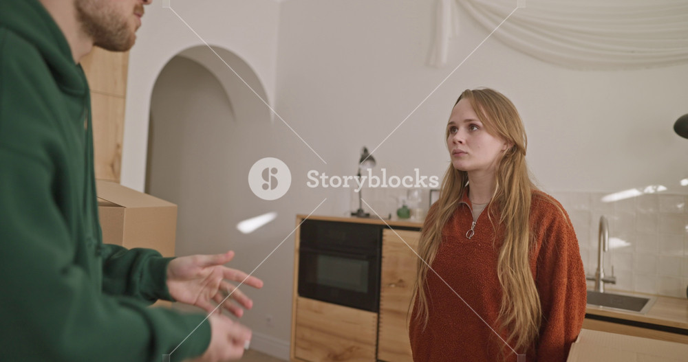 Over her shoulder a blonde girl swears with her boyfriend and gives him the keys and then turns away during a quarrel at home