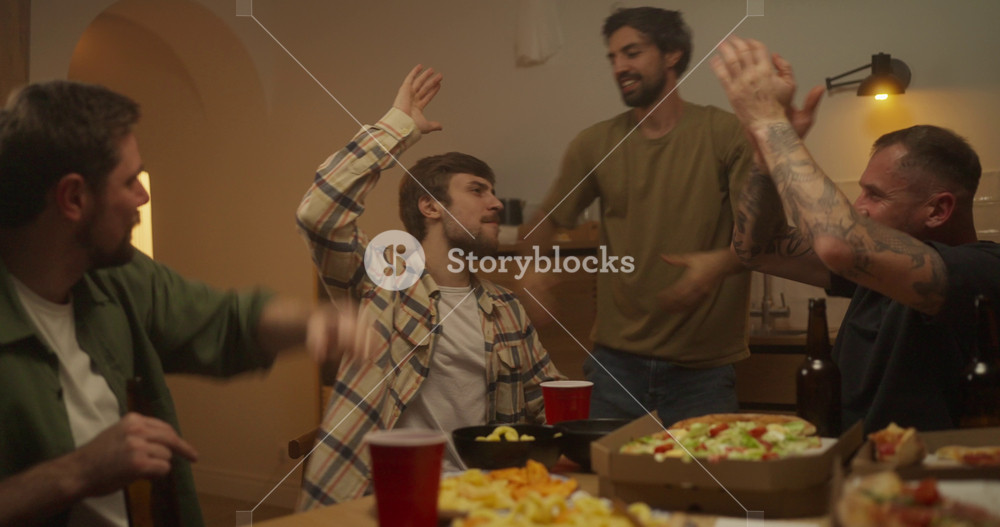 A group of happy and cheerful friends applaud while their friend finishes his to the bottom during a cheerful bachelor party at home in the