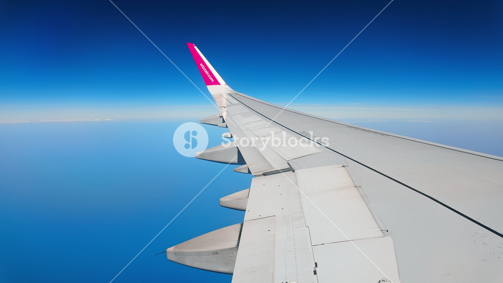 Wizz Air Valencia, Spain - March 18, 2026: airplane window porthole view dark cabin wing winglet blue sky altitude cruising passenger seat travel freedom tourism international flight Europe vacation