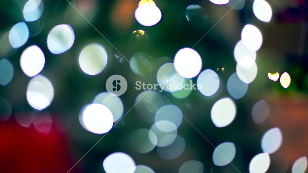 Bright and colorful lights illuminate a Christmas tree, creating a cheerful holiday mood. The scene captures the joy and warmth of the festive season with soft bokeh effects.