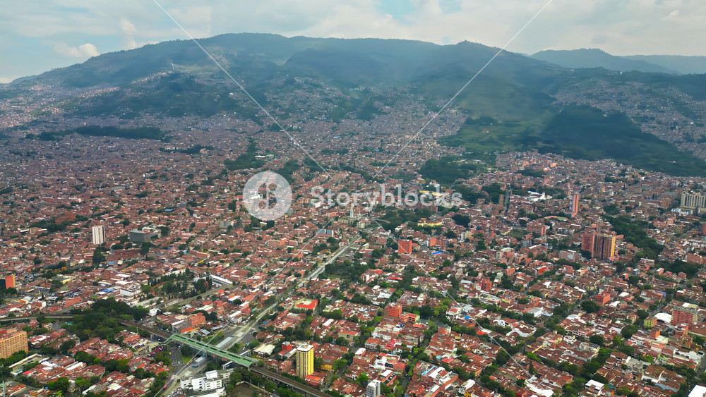 Aerial drone view of of Medellin, Colombia, showing the dense urban area surrounded by green mountains in slow motion